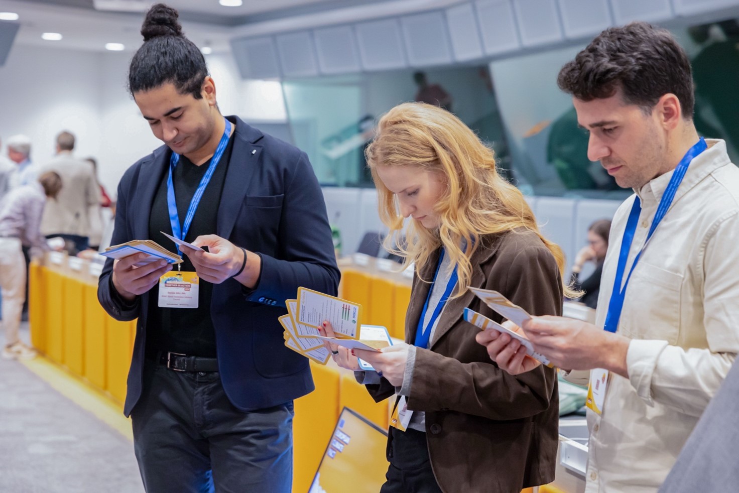 One woman and two men looking at cards